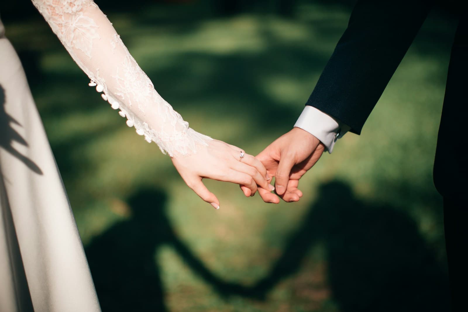 A close-up of a couple holding hands outdoors. Temporary editorial photograph.