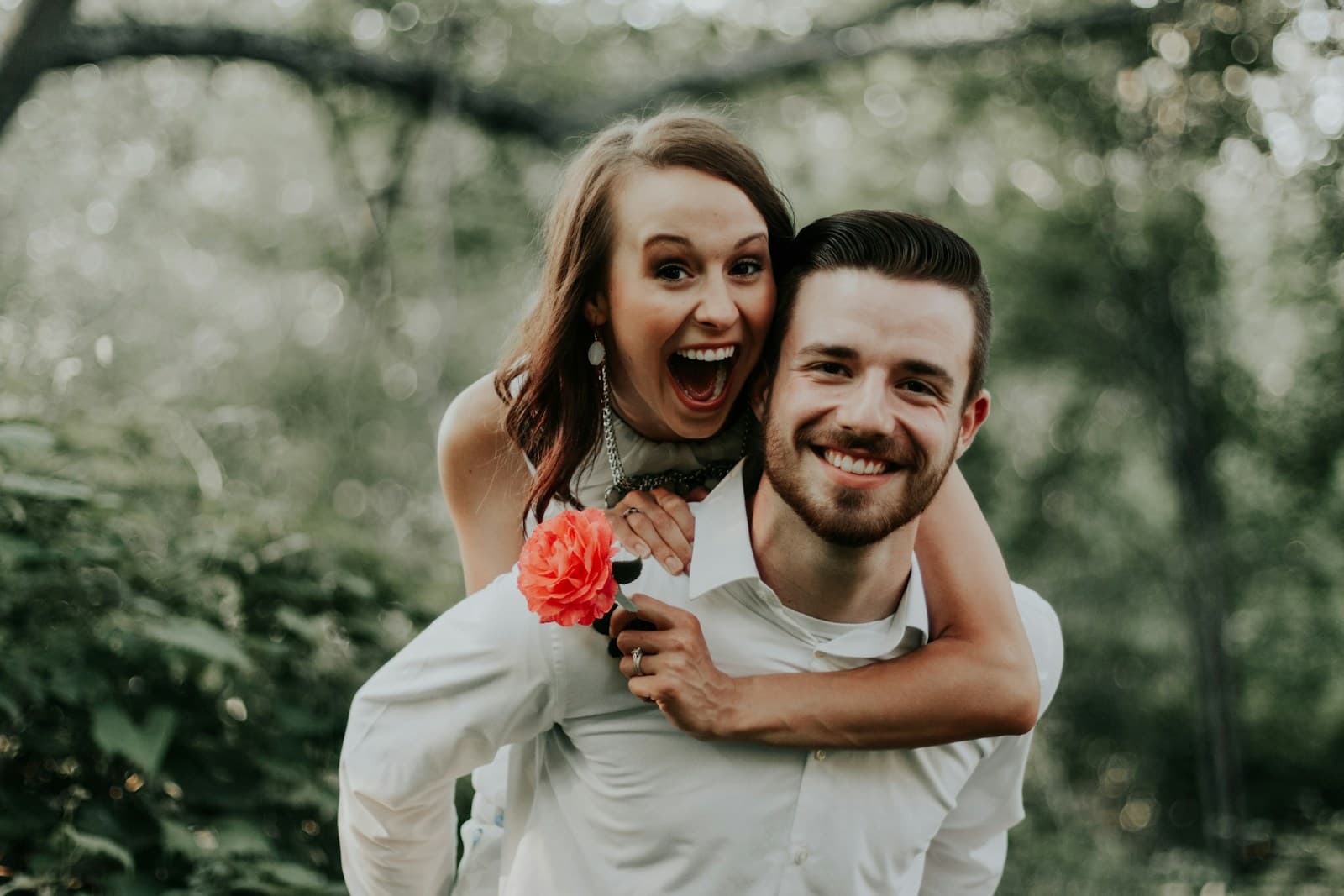 A couple sharing a playful piggyback ride outdoors. Temporary editorial photograph.
