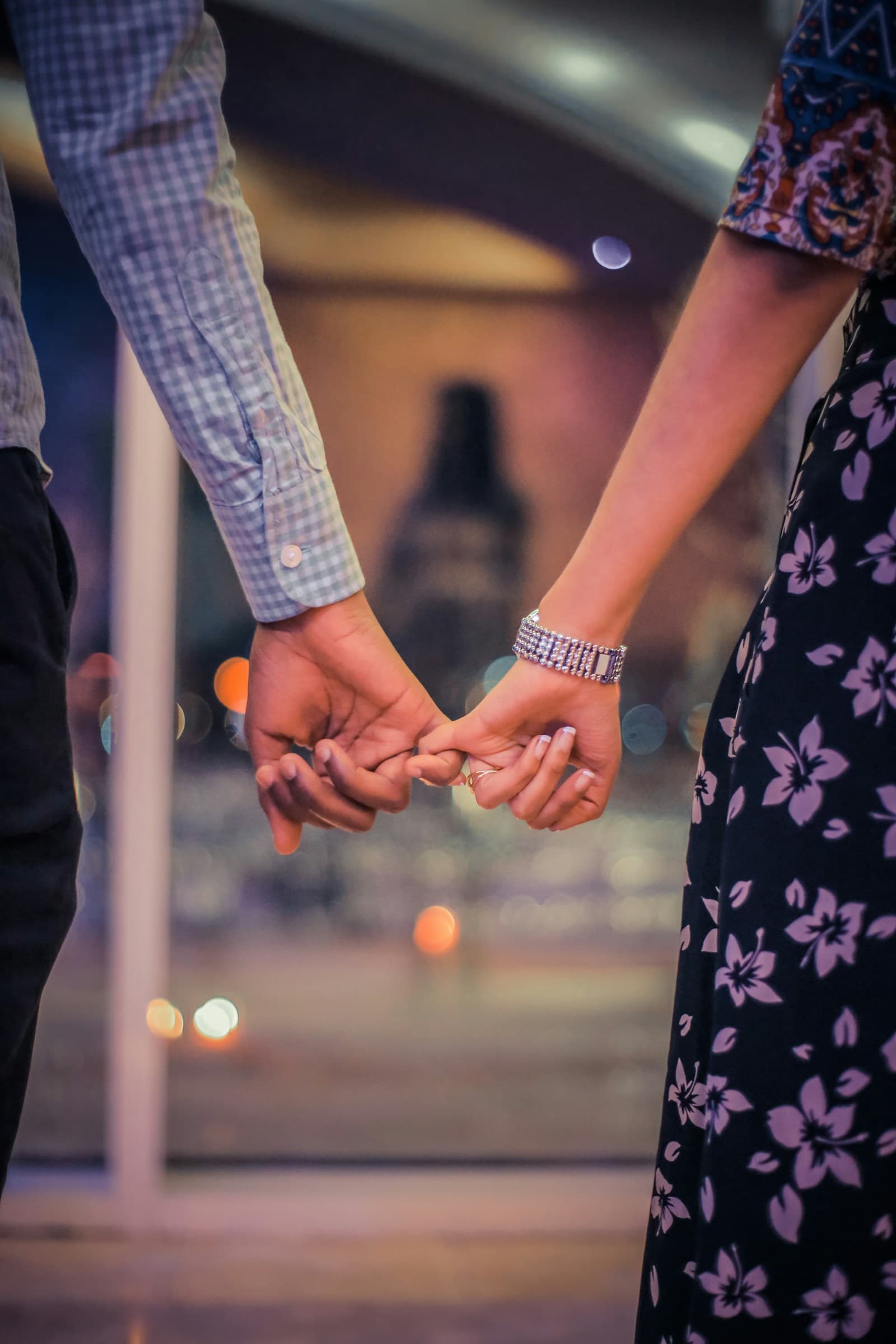 Two people holding hands beside a stone building. Temporary editorial photograph.