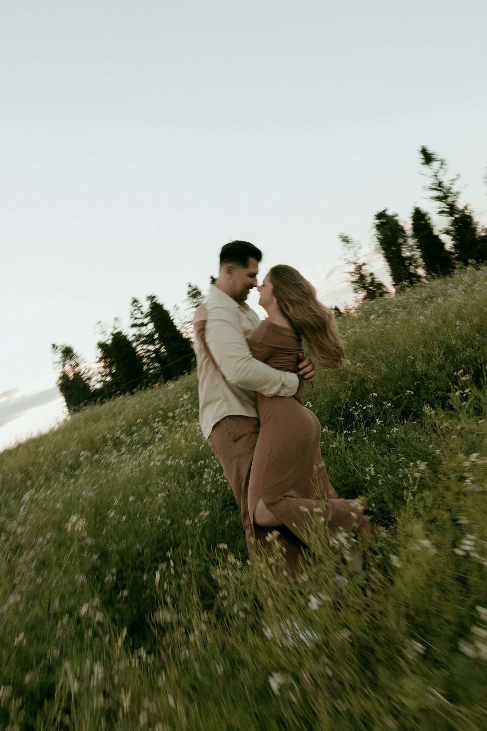 A couple holding each other in a quiet green meadow. Temporary editorial photograph.