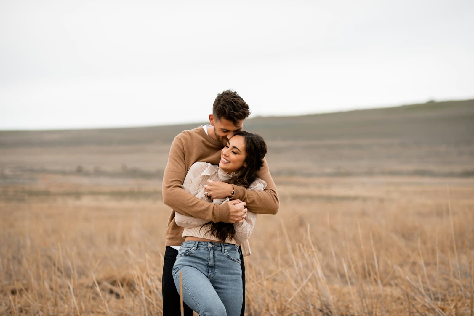 A couple embracing in a wide golden field. Temporary editorial photograph.