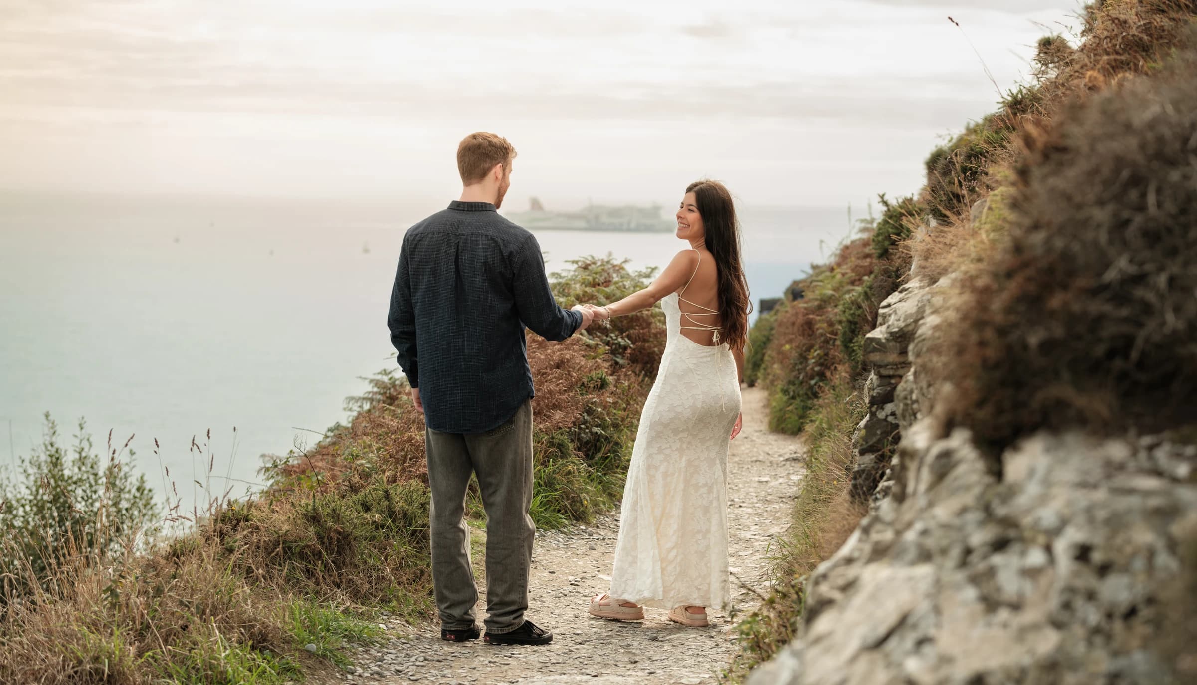 Alice and Jamie holding hands on a coastal path.
