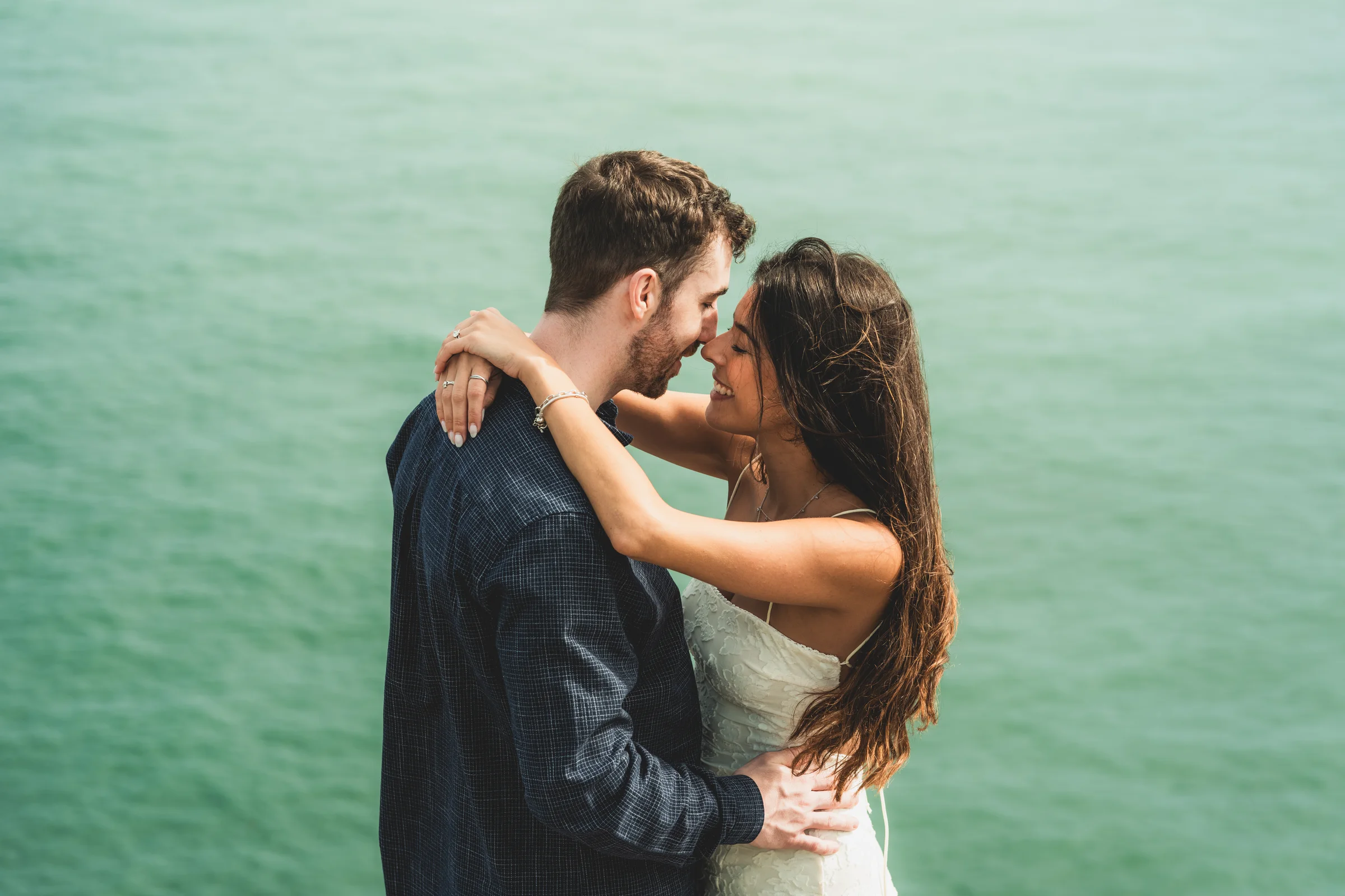 Alice and Jamie embracing by the sea